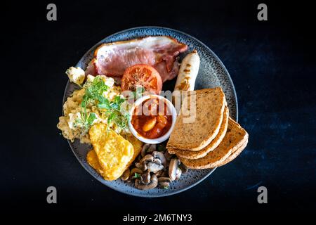 Vista dall'alto di una colazione inglese completa su un tavolo di pietra nera Foto Stock