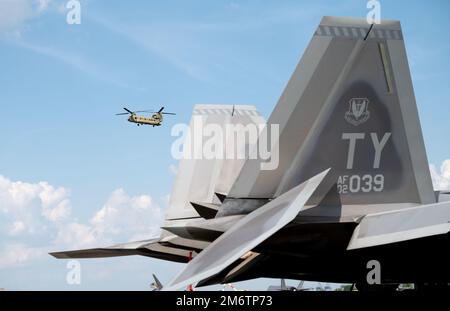 Un CH-47 Chinook si trova dietro la coda di un F-22 Raptor assegnato alla 325th Fighter Wing, Eglin Air Force base, Florida, al Savannah Hilton Head International Airport, 5 maggio 2022. La 325th Fighter Wing ha inviato più di 200 persone e 22 aerei a partecipare a Sentry Savannah, un esercizio di addestramento vicino ai pari ospitato dal Air Dominance Center della Guardia Nazionale aerea. Foto Stock