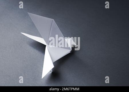 Carta bianca colomba origami isolato su uno sfondo grigio Foto Stock