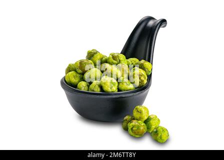 Vista dei piselli verdi rivestiti di wasabi secchi e croccanti in una tazza di ceramica nera isolata su sfondo bianco. Foto Stock