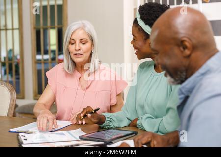 Coppia anziana diversa che parla con la consulente finanziario femminile afro-americana Foto Stock