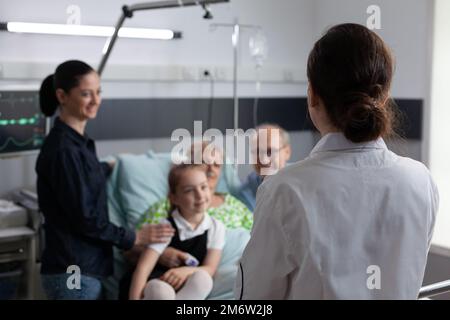 Infermiere che visita la stanza felice del paziente anziano in recupero. Nonna malata sorridente famiglia che chiacchiera con un medico geriatrico femminile non identificato nella stanza della clinica medica. Foto Stock