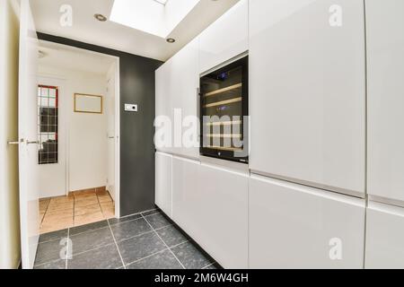 una cucina moderna con armadi bianchi e ripiani neri sulla parete, in uno spazio open space per cucinare Foto Stock