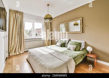 una camera da letto con un letto, comò e specchio sulla parete di fronte al letto c'è un pavimento in legno Foto Stock