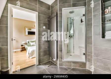 un bagno moderno con pareti in piastrelle grigie e finiture bianche sulla  porta della doccia, articoli da toeletta e specchio nell'angolo Foto stock  - Alamy