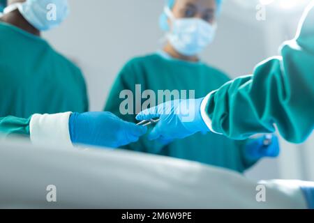 Basso angolo di passaggio degli strumenti chirurgici nella sala operatoria durante il funzionamento, con spazio di copia Foto Stock