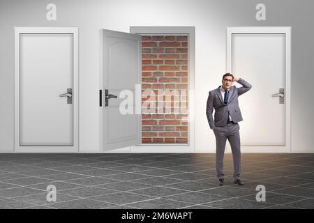 Uomo d'affari che guarda senza uscita con porta in mattoni Foto Stock