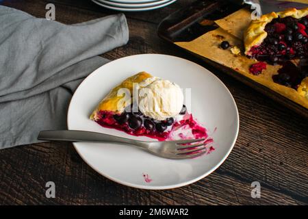 Fetta di torta mista di frutti di bosco con gelato alla vaniglia: Torta rustica da dessert fatta con lamponi, mirtilli e more Foto Stock