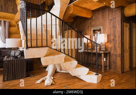 Scale di legno sbiancate con ringhiera in ferro battuto nero nel soggiorno all'interno di una lussuosa casa in legno stile cottage. Foto Stock