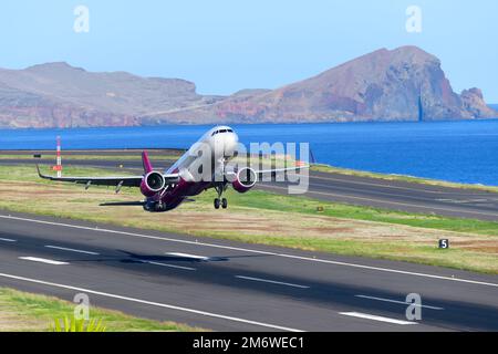Decollo dell'aeromobile Wizz Air Airbus A321. WizzAir Aircraft A321 durante il decollo dall'aeroporto di Madeira (aeroporto di Funchal) con paesaggio dietro. Foto Stock