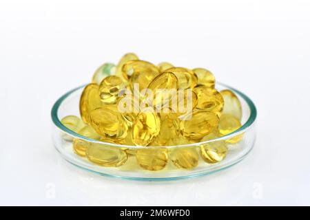 Capsule di gelatina molle di olio essenziale nel piatto di vetro isolato su fondo bianco. Campione di capsule di olio per la pubblicità. Foto Stock