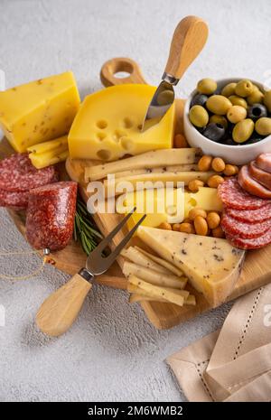 Diversi tipi di formaggi e salumi. Vista dall'alto su sfondo bianco. Formaggi assortiti con noci, cracker, olive, sala Foto Stock