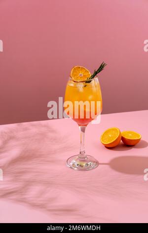 Tequila cocktail all'alba. Rinfrescante bevanda estiva colorata su sfondo rosa con foglia di palma ombra. Menu di bevande del bar. Foto Stock