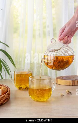 Tè verde gelsomino in teiera di vetro sul tavolo. Il tè caldo è nelle tazze di vetro. Teiera e tazza di tè con tè verde sul tavolo. COP Foto Stock