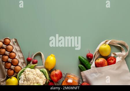 Concetto di shopping zero rifiuti su sfondo verde. Verdura fresca e frutta in sacchetti di cotone ecologico sul tavolo. Foto Stock