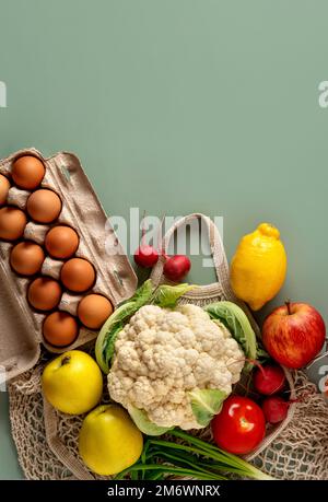 Concetto di shopping zero rifiuti su sfondo verde. Verdura fresca e frutta in sacchetti di cotone ecologico sul tavolo. Foto Stock