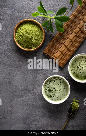 Tè Matcha in polvere e accessori da tè su sfondo scuro. Foto Stock