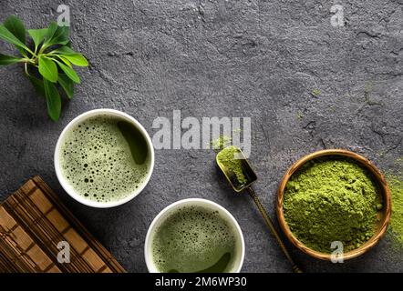Tè Matcha in polvere e accessori da tè su sfondo scuro. Foto Stock