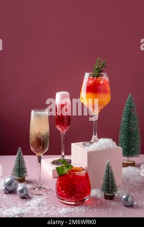 Cocktail di agrumi festosi sui podi. Assortimento di bevande fresche di Natale. Cocktail di sangria rosa e rossa, jingle di melograno, Foto Stock