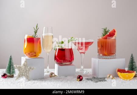 Cocktail di agrumi festosi sui podi. Assortimento di bevande fresche di Natale. Cocktail sangria rosa e rossa, champagne, melograno Foto Stock