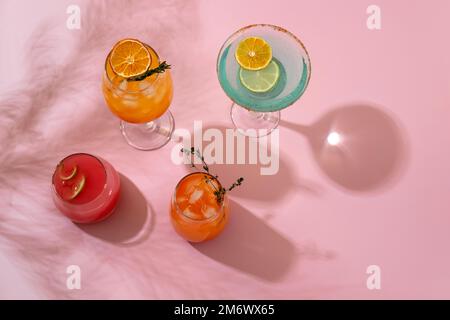 Cocktail tropicali colorati. Rinfrescanti bevande estive colorate su sfondo rosa con foglie di palma ombra. Menu di bevande del bar. Foto Stock