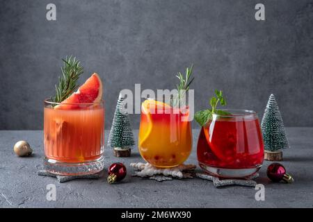 Tre cocktail festosi con vari agrumi. Assortimento di bevande alcoliche di Natale. Cocktail di sangria rosa e rossa, melograno Foto Stock