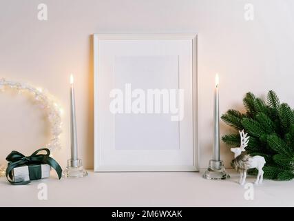 Mock su cornice con decorazioni natalizie. Composizione natalizia con ramo di abete, cervo, candela e stelle d'argento su bac bianco Foto Stock