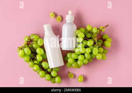 Due bottiglie bianche per marcare a caldo con olio di semi d'uva. Prodotto cosmetico per la cura della pelle. Mock cosmetico su sfondo rosa. Foto Stock