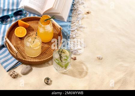 Drink estivi esotici su un vassoio di vimini sulla spiaggia con sabbia bianca. Vacanza estiva al mare e concetto di viaggio. Bevande estive esotiche. Foto Stock