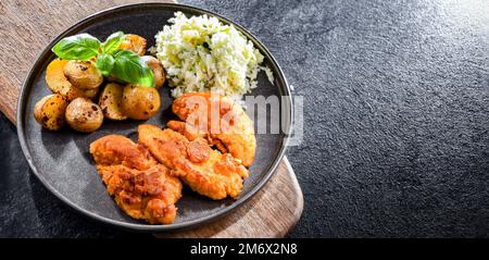 Cotolette di pollo impanate servite con patate e cavolo. Foto Stock