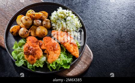 Cotolette di pollo impanate servite con patate e cavolo. Foto Stock