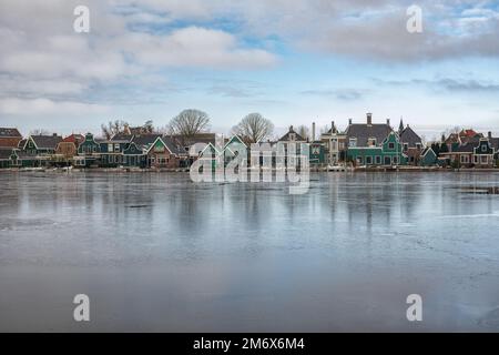 Il verde caratteristico Zaan case con il mulino a vento lungo le rive del fiume Zaan in Zaandijk nei Paesi Bassi Foto Stock