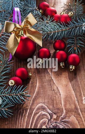 grande composizione di giocattoli di natale rosso baubles oro arco colorato e rami di abete su vecchio asse di legno con piccolo spazio di copyspace Foto Stock