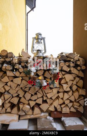 La legna da ardere sul portico innevato della casa viene raccolta per l'inverno. Riscaldamento di alloggi con camino a stufa, risparmio elettrico Foto Stock