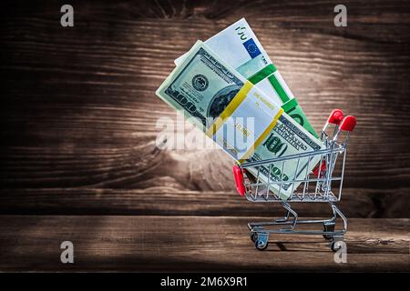 pacchetti di dollari e euro in carrello di acquisto su legno d'annata Foto Stock