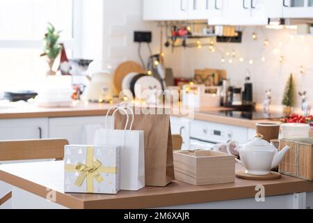 Confezione regalo e pacchetti sono su tavolo da cucina decorato per Natale. I pasti presenti e pronti vengono consegnati e preparati per il n Foto Stock