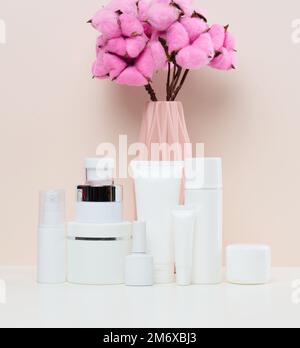 Vasetti e tubi in plastica bianca per cosmetici liquidi su fondo bianco. Branding, pubblicità Foto Stock