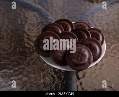 foto sul tavolo di vetro è un piatto con biscotti al cioccolato in scaglie in glassa Foto Stock