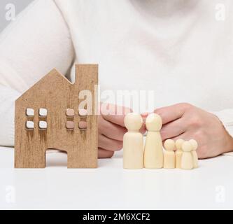 Casa di legno e figure di una famiglia. Concetto di assicurazione immobiliare, famiglia felice Foto Stock