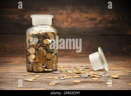 Vaso di vetro riempito di monete d'oro Foto Stock