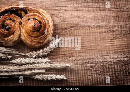 Pancia di uva passa fresca di forno mucchio di spighe di grano su tavola di legno di quercia cibo e bevande concetto. Foto Stock