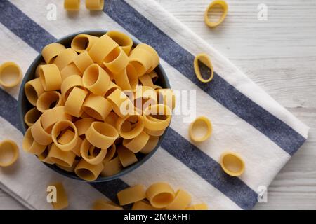 Pasta cruda non cotta Calamarata in una ciotola, vista dall'alto. Giacitura piana, sovratesta, dall'alto. Spazio di copia. Foto Stock