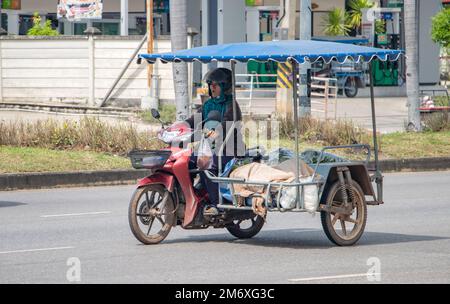 RATCHABURI, THAILANDIA, 16 2022 NOVEMBRE, Una donna cavalca una moto con un sidecar pieno carico Foto Stock