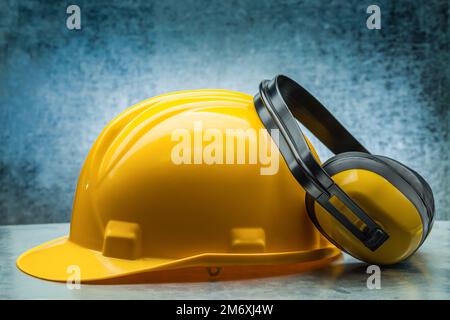 costruzione casco giallo e auricolari su sfondo metalico Foto Stock