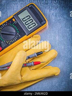 Tester elettrico digitale Guanti di protezione su sfondo metallico concetto di elettricità. Foto Stock