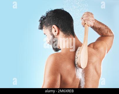 Doccia, pulizia e uomo con spazzola, spruzzi d'acqua e sapone in studio per  il benessere, l'igiene e la cura del corpo. Cura della pelle, cura di sé e  maschio con schiuma, bagno