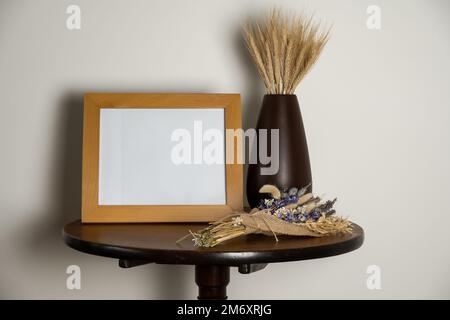 mockup stile di vita tavolo interno piedistallo con quadro vuoto vaso telaio di fogli di grano secco e fiori secchi sul tavolo Foto Stock