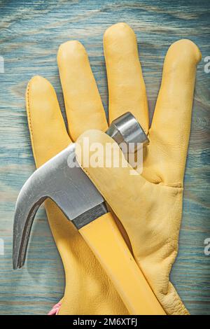 Composizione del guanto di protezione per martello a artiglio su un piano di legno. Foto Stock