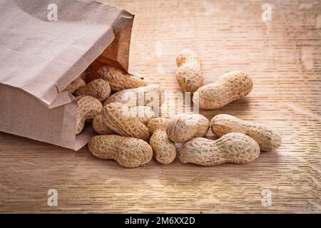 arachidi di vercion orizzontali versate da sacchetto di carta su cibo di legno e bere ancora vita Foto Stock
