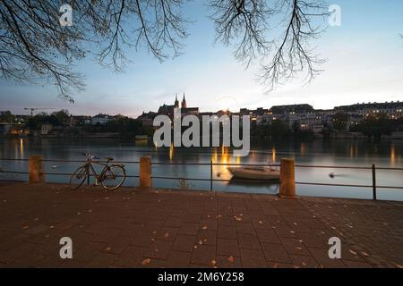 basilea svizzera, la passeggiata sul reno di sera. Sullo sfondo la cattedrale e la ruota panoramica della fiera autunnale. Foto Stock